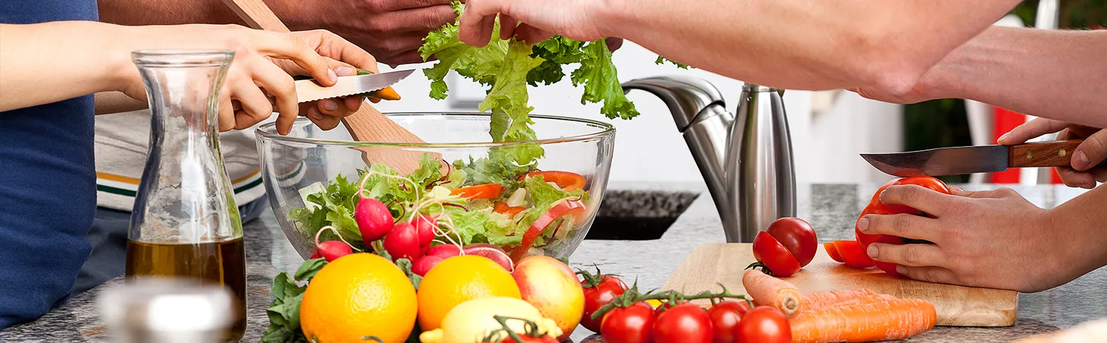 Personas cortando productos y preparando una ensalada